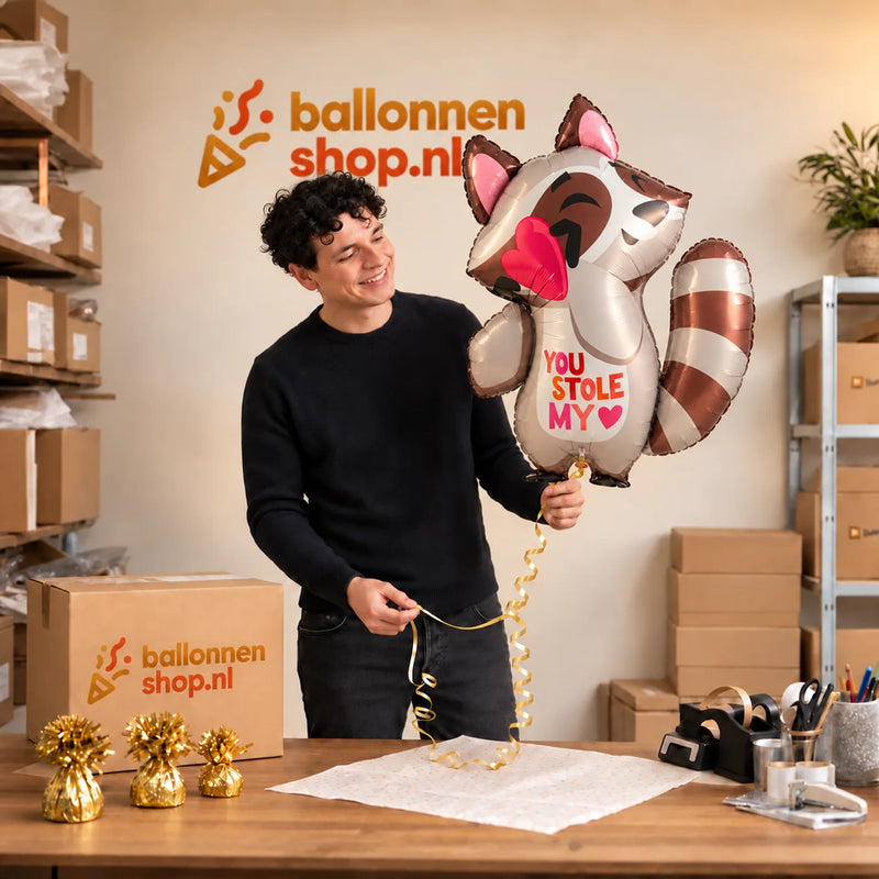 Jesse houdt de You Stole My Heart Wasbeer – Met een Zachte Knipoog vast in de warme inpakruimte van Ballonnenshop.nl.