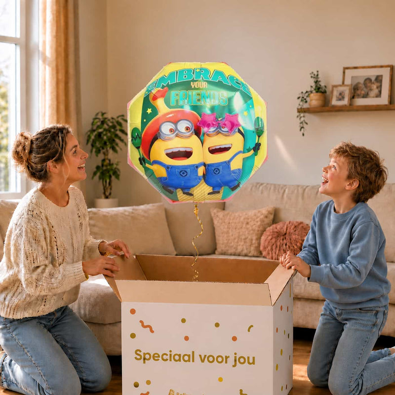 Moeder en jongen bekijken een Minion Embrace Your Friends-ballon van 65 cm met gouden lint boven de geopende cadeaudoos ‘Speciaal voor jou’.