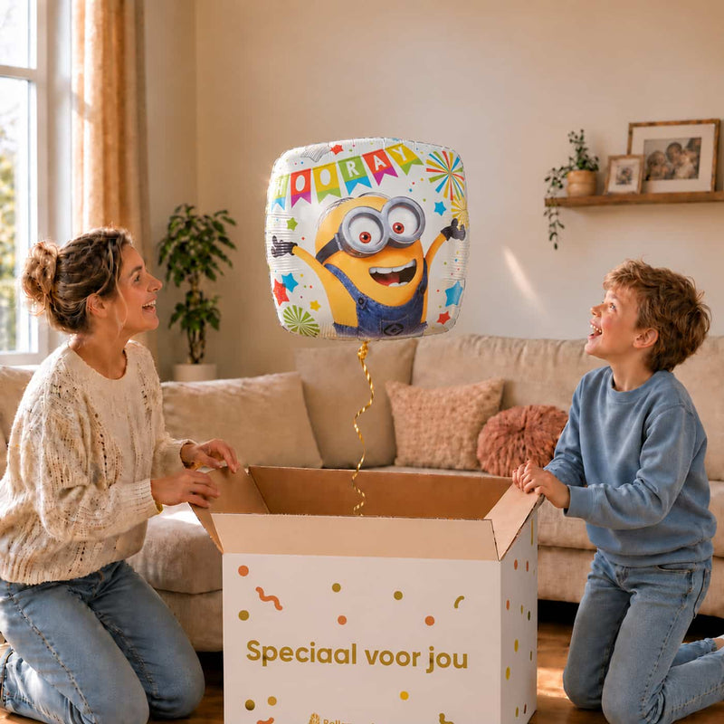 Moeder en jongetje bij een Minion Hooray heliumballon van 46 cm boven een open cadeaudoos.