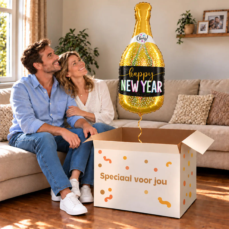 Een volwassen stel kijkt blij naar New Year Champagne XL Ballon boven een grote Speciaal voor jou-doos in een warme woonkamer.