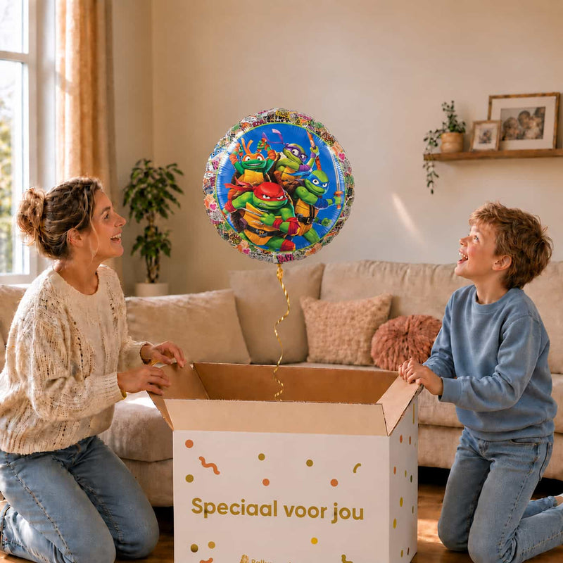Moeder en jongen pakken de Ninja Turtles ballon van 46 cm uit een feestelijke cadeaudoos.