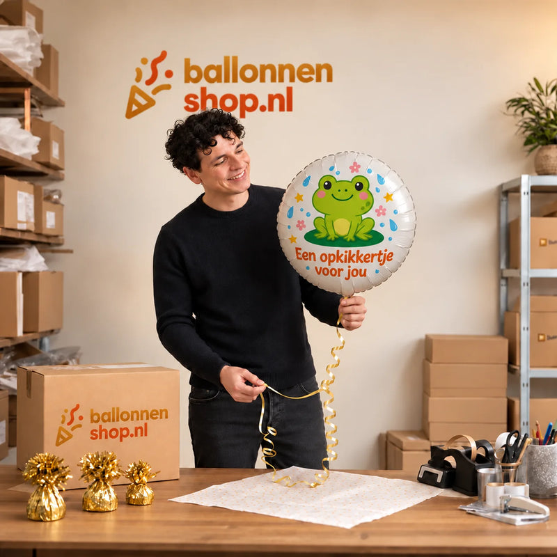 Jesse houdt de Opkikkertje Voor Jou Ballon vast in de warme werkplaats van Ballonnenshop.nl.