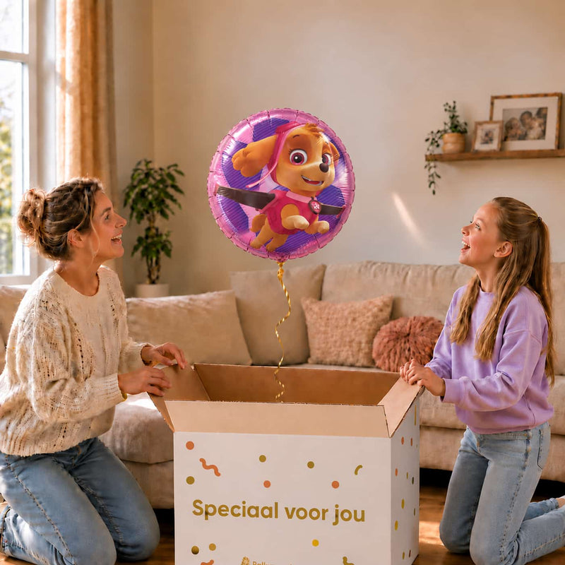 Moeder en meisje bekijken een roze Skye PAW Patrol heliumballon van 46 cm boven de geopende cadeaudoos.