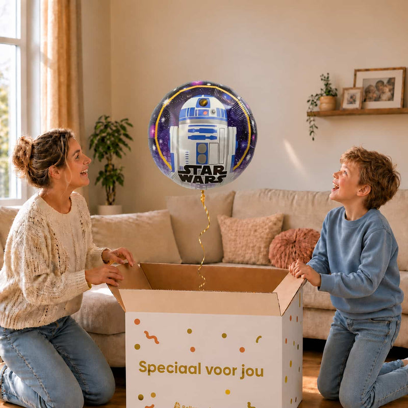Moeder en jongen bekijken de ballon Star Wars R2D2 Helium Ballon in zacht warm licht boven de geopende cadeaudoos ‘Speciaal voor jou’.