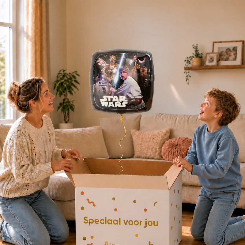 Moeder en jongen bekijken de ballon The Light Side Star Wars Ballon in zacht warm licht boven de geopende cadeaudoos ‘Speciaal voor jou’.