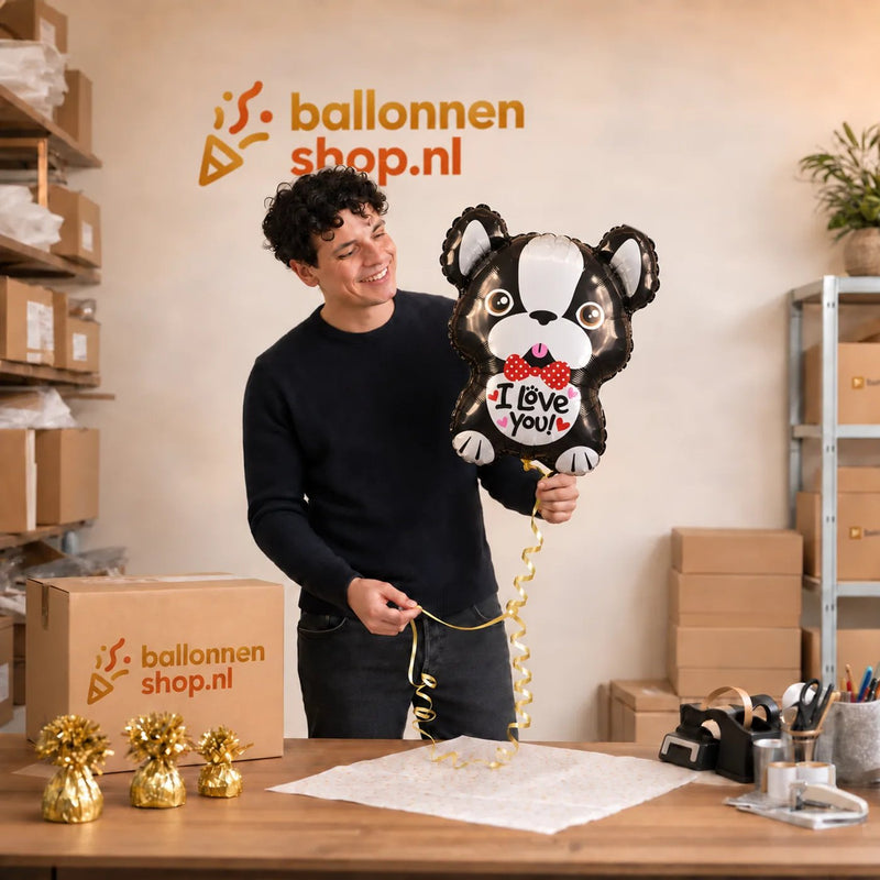 Jesse houdt de Valentijns Hond I Love You Ballon vast in de warme werkplaats van Ballonnenshop.nl.