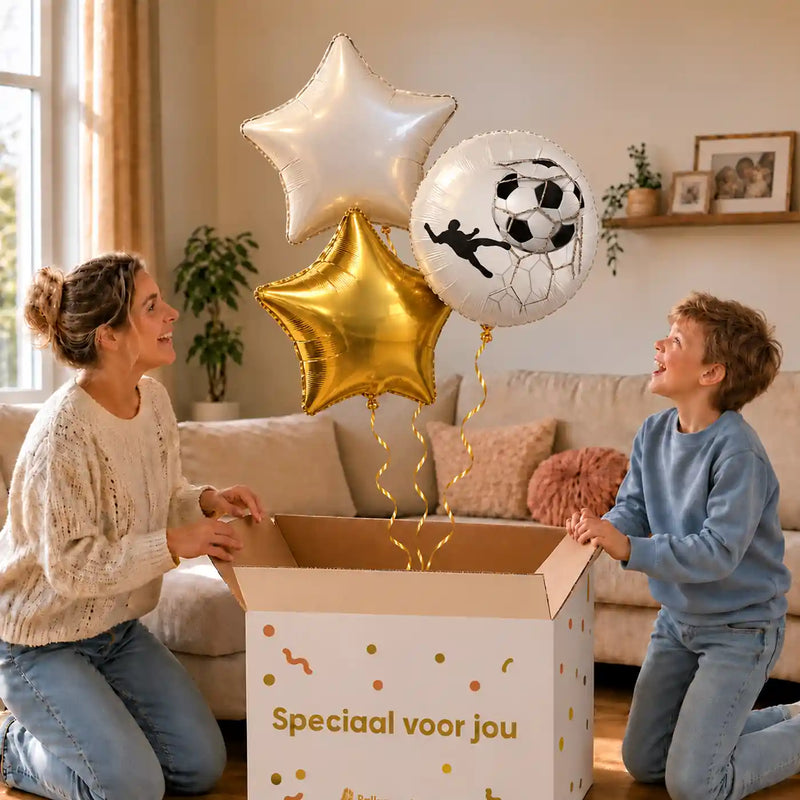 Voetbal Trosje Goud/Wit/Zwart: moeder en zoon pakken het heliumgevulde ballonnentrosje uit een Speciaal voor jou-doos, met natuurlijk gekrulde gouden linten.
