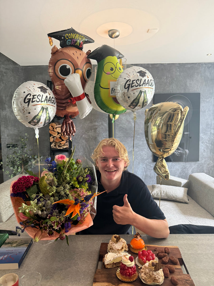 Sil viert dat hij geslaagd is voor zijn examens, met ballonnen, bloemen en gebak.