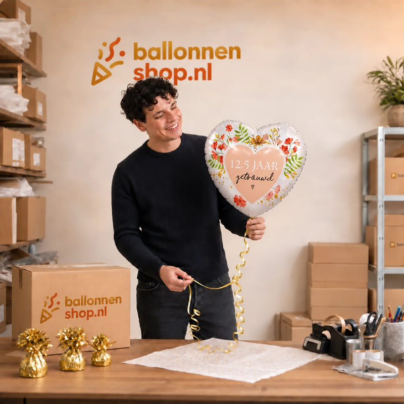 Jesse houdt de 12.5 Jaar Getrouwd Helium Ballon vast in de warme werkplaats van Ballonnenshop.nl.