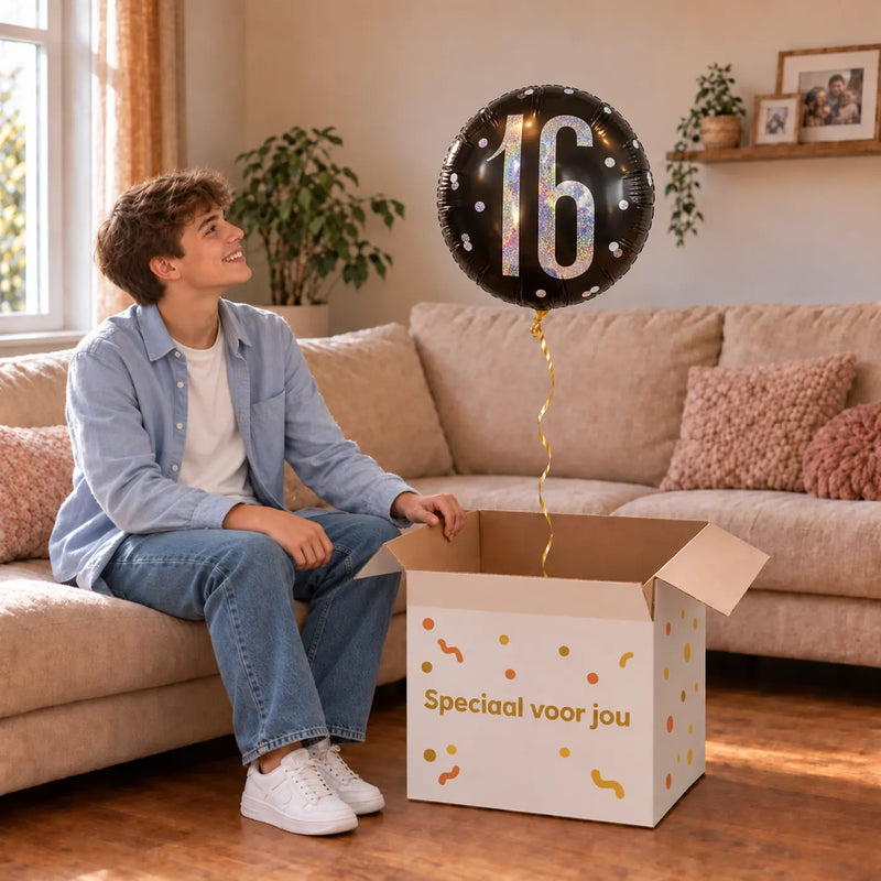Jongen viert 16 jaar met 16 Jaar Helium Ballon Zwart uit een cadeaudoos van Ballonnenshop.nl