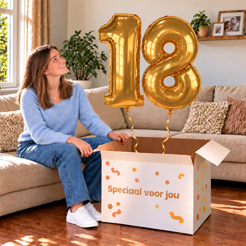 18 Jaar Cijfer Ballonnen Goud met twee heliumgevulde cijferballonnen en een jarige in een warme woonkamer