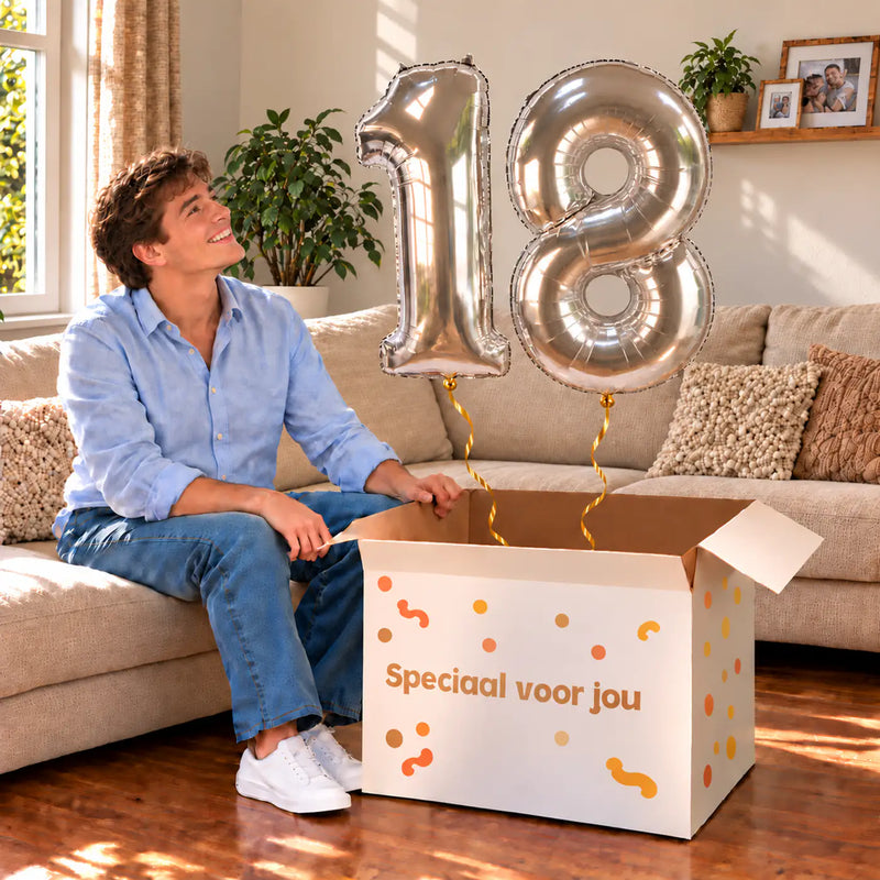 18 Jaar Cijfer Ballonnen Zilver met twee heliumgevulde cijferballonnen en een jarige in een warme woonkamer