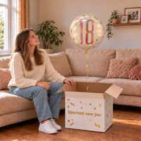 Vrouw viert 18 jaar met 18 Jaar Helium Ballon Wit uit een cadeaudoos van Ballonnenshop.nl
