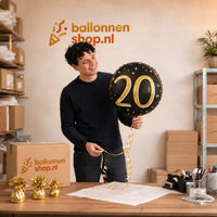 Jesse houdt de 20 Jaar Helium Ballon Zwart/Goud vast in de warme werkplaats van Ballonnenshop.nl.