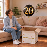 Man viert 20 jaar met 20 Jaar Helium Ballon Zwart/Goud uit een cadeaudoos van Ballonnenshop.nl