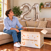 21 Jaar Cijfer Ballonnen Zilver met twee heliumgevulde cijferballonnen en een jarige in een warme woonkamer