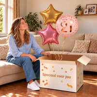 Een jarige met 21 Jaar Trosje Roze/Goud/Rose Goud boven een open Speciaal voor jou-doos in een warme woonkamer.