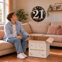 Man viert 21 jaar met 21 Jaar Ballon Zwart/Zilver/Goud uit een cadeaudoos van Ballonnenshop.nl