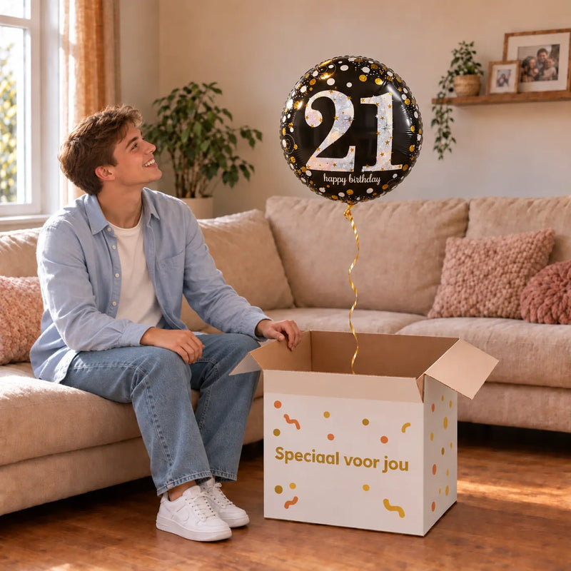 Man viert 21 jaar met 21 Jaar Ballon Zwart/Zilver/Goud uit een cadeaudoos van Ballonnenshop.nl