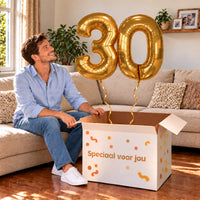 30 Jaar Cijfer Ballonnen Goud met twee heliumgevulde cijferballonnen en een jarige in een warme woonkamer