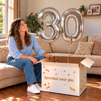 30 Jaar Cijfer Ballonnen Zilver met twee heliumgevulde cijferballonnen en een jarige in een warme woonkamer