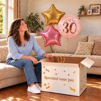 Een jarige met 30 Jaar Trosje Roze/Goud/Rose Goud boven een open Speciaal voor jou-doos in een warme woonkamer.