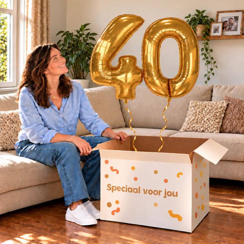 40 Jaar Cijfer Ballonnen Goud met twee heliumgevulde cijferballonnen en een jarige in een warme woonkamer