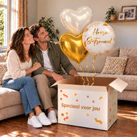 Een feestelijk huwelijksmoment met Hoera Getrouwd Trosje Ballonnen boven een open Speciaal voor jou-doos in een warme woonkamer.