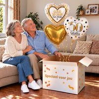 Een feestelijk huwelijksmoment met 50 Jaar Getrouwd Trosje Goud boven een open Speciaal voor jou-doos in een warme woonkamer.