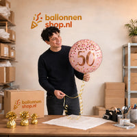 Jesse houdt de 50 Jaar Helium Ballon Roze vast in de warme werkplaats van Ballonnenshop.nl.