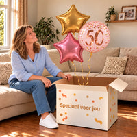 Een jarige met 50 Jaar Trosje Roze/Goud/Rose Goud boven een open Speciaal voor jou-doos in een warme woonkamer.