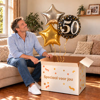 Een jarige met 50 Jaar Trosje Zilver/Zwart/Goud boven een open Speciaal voor jou-doos in een warme woonkamer.