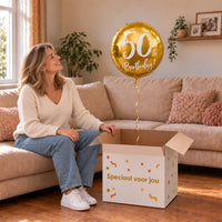 Vrouw viert 50 jaar met 50th Birthday Helium Ballon Goud uit een cadeaudoos van Ballonnenshop.nl