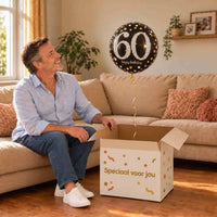Man viert zijn 60e verjaardag met een zwart-zilver-gouden heliumballon uit een cadeaudoos van Ballonnenshop.nl