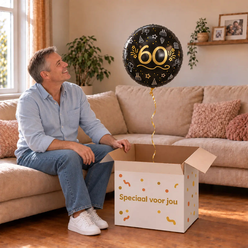 Man viert 60 jaar met 60 Ballon Zwart/Zilver/Goud uit een cadeaudoos van Ballonnenshop.nl