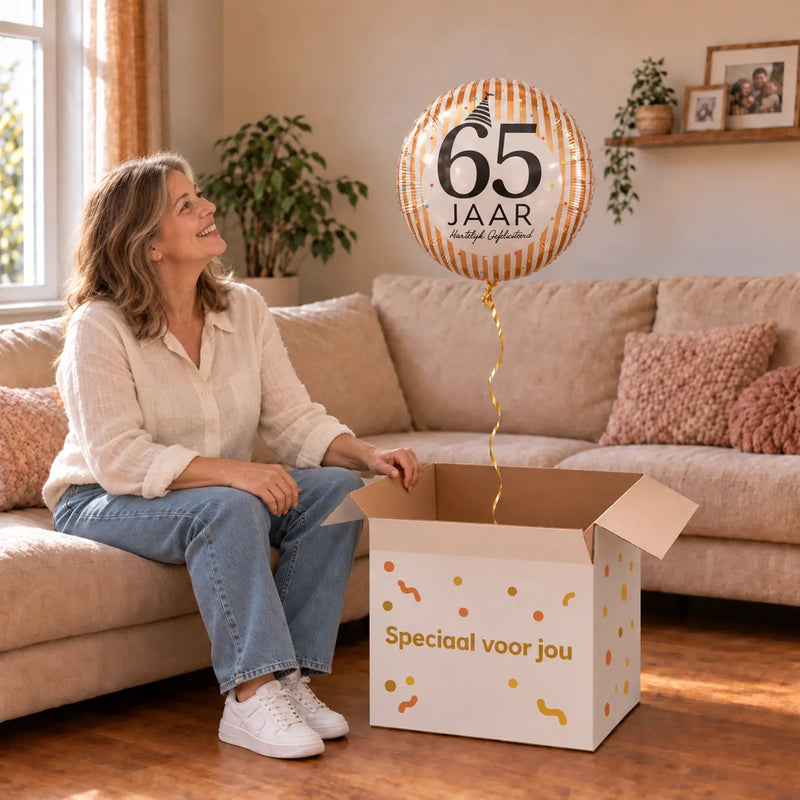 Vrouw viert 65 jaar met 65 Jaar Hartelijk Gefeliciteerd uit een cadeaudoos van Ballonnenshop.nl
