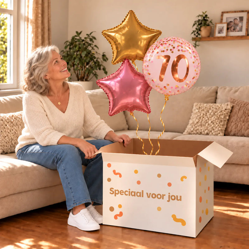 Een jarige met 70 Jaar Trosje Roze/Goud/Rose Goud boven een open Speciaal voor jou-doos in een warme woonkamer.