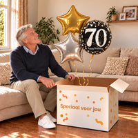 Een jarige met 70 Jaar Trosje Zilver/Zwart/Goud boven een open Speciaal voor jou-doos in een warme woonkamer.