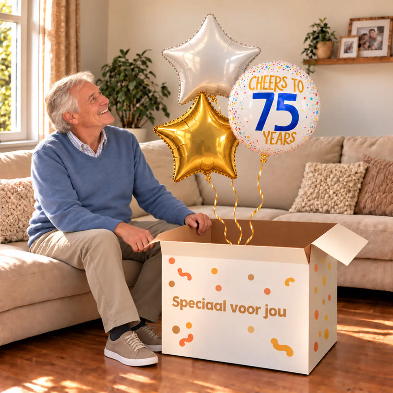 Een jarige met 75 Jaar Trosje Wit/Goud/Blauw boven een open Speciaal voor jou-doos in een warme woonkamer.