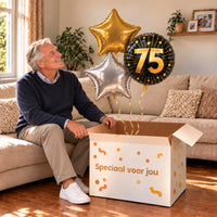 Een jarige met 75 Jaar Trosje Zilver/Zwart/Goud boven een open Speciaal voor jou-doos in een warme woonkamer.