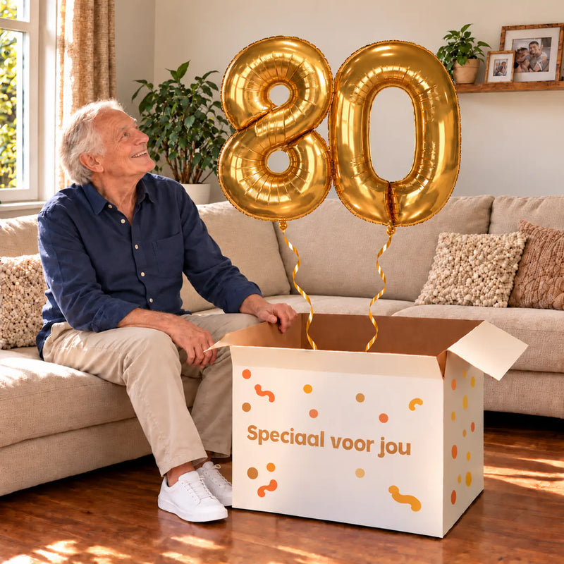 80 Jaar Cijfer Ballonnen Goud met twee heliumgevulde cijferballonnen en een jarige in een warme woonkamer