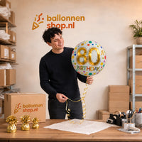 Jesse houdt de 80 Jaar Helium Ballon Stippen vast in de warme werkplaats van Ballonnenshop.nl.