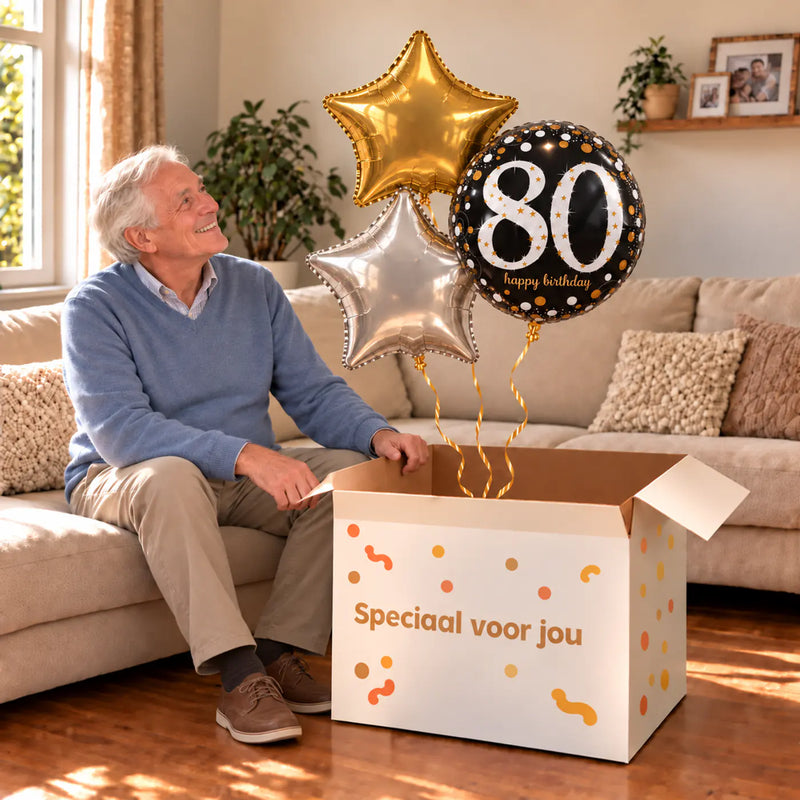 Een jarige met 80 Jaar Trosje Zilver/Zwart/Goud boven een open Speciaal voor jou-doos in een warme woonkamer.