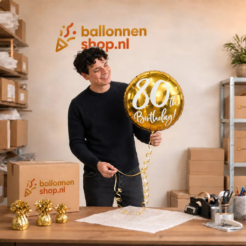 Jesse houdt de 80th Birthday Helium Ballon Goud vast in de warme werkplaats van Ballonnenshop.nl.