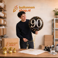 Jesse houdt de 90 Jaar Ballon Zwart/Zilver/Goud vast in de warme werkplaats van Ballonnenshop.nl.