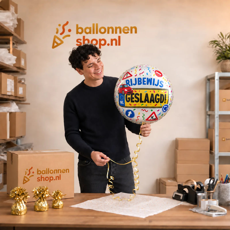 Jesse houdt de Auto Rijbewijs Geslaagd Helium Ballon - Gevuld Met Helium - 46 cm vast in de warme werkplaats van Ballonnenshop.nl.