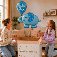 Baby Boy Blauw Olifantje XL zweeft boven een geopende cadeaudoos bij een moeder en meisje in een warme woonkamer.