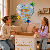 Baby Boy Hart Sterren XL Ballon zweeft boven een geopende cadeaudoos bij een moeder en meisje in een warme woonkamer.
