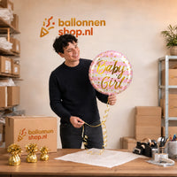 Jesse houdt de Baby Girl Helium Ballon vast in de warme werkplaats van Ballonnenshop.nl.