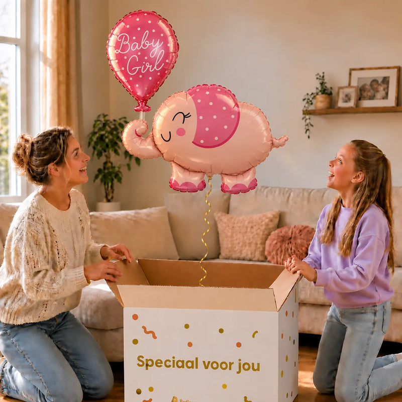 Baby Girl Roze Olifantje XL zweeft boven een geopende cadeaudoos bij een moeder en meisje in een warme woonkamer.